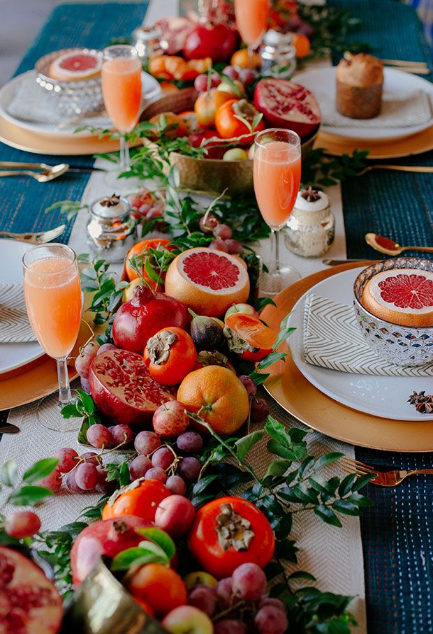 table with fruit arrangement, plates, and mimosas