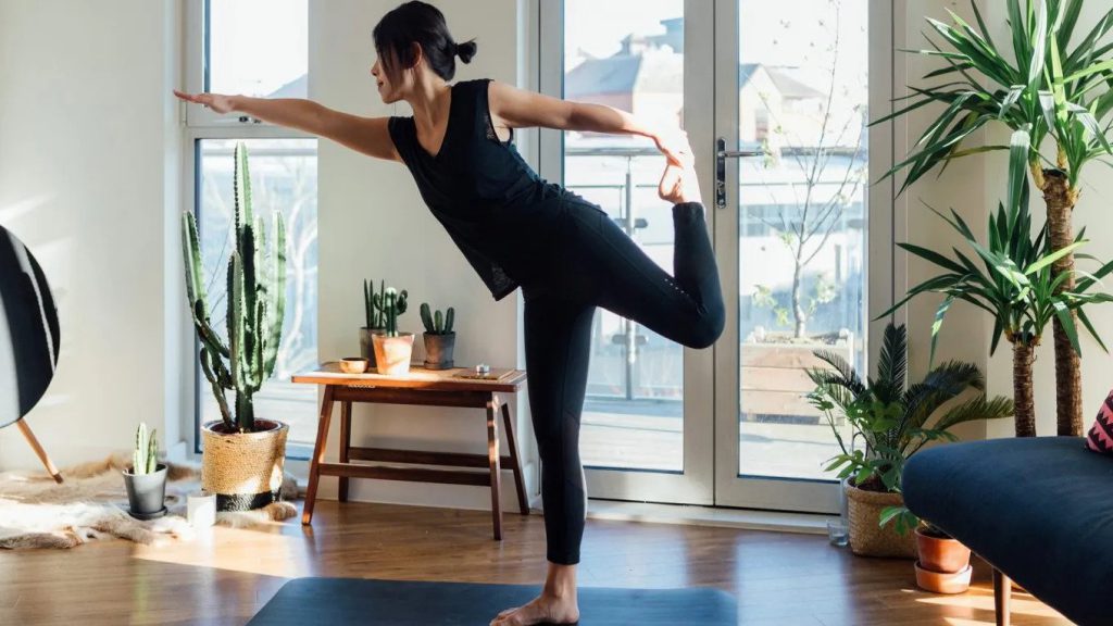 woman doing yoga at home with houseplants